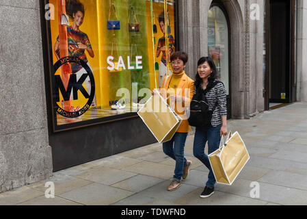 London, UK. 19 June 2019. Tourists carry their Michael Kors shopping bags on Regent Street as the Summer Sales season begins, with stores offering large discounts to clear inventories. As retailers