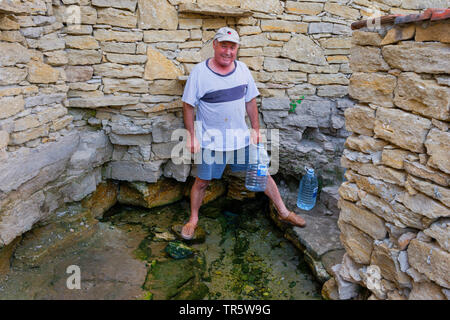 man getting his mineral water from the well, Moldova, Delacau Stock Photo