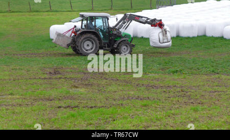 tractor on a meadow with silage bales, Germany Stock Photo