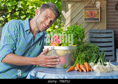 young man with fruit and vegetable basket, Germany Stock Photo