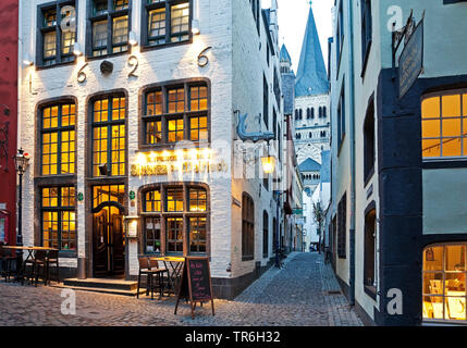 Salzgasse with restaurant, view through narrow lane to Great St. Martin Church in the evening, Germany, North Rhine-Westphalia, Cologne Stock Photo