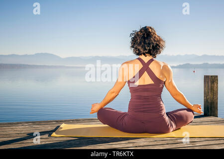 woman doing yoga exercises at a lake, Germany, Bavaria Stock Photo