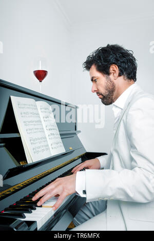 young man in white suit at a piano, Germany Stock Photo
