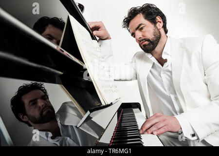 young man in white suit at a piano, Germany Stock Photo