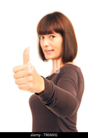 good looking woman with half long brown hair and fringe showing thump up, Germany Stock Photo