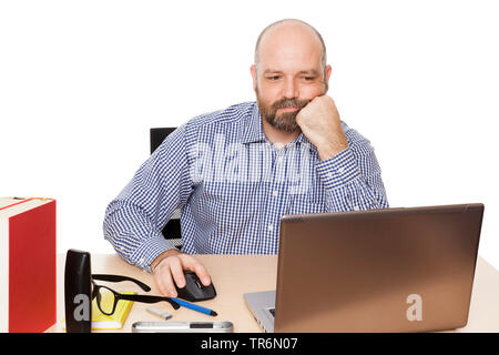 man with beard sitting at the writing desk with laptop, surfing, cutout, Germany Stock Photo