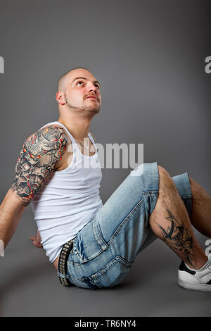 young tattooed man with bald head and beard with muscelshirt and jeans, Germany Stock Photo