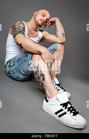 young tattooed man with bald head and beard with muscelshirt and jeans, Germany Stock Photo