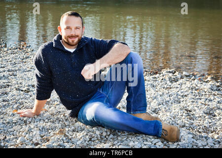 handsome man sitting by the waterside of a river, Germany Stock Photo