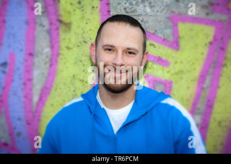 young man in fornt of a graffiti wall, Germany Stock Photo