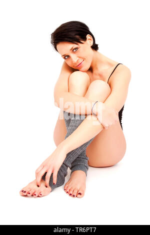 young woman in sportive clothing sitting on white ground, Germany Stock Photo