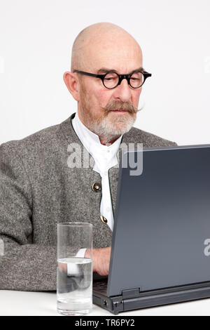 old man with bald head and grey beard at a laptop, Germany, Bavaria Stock Photo