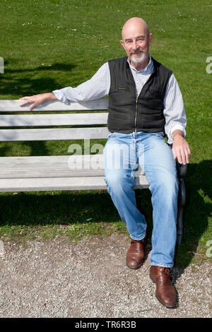 old man with a grey beard on a park bench, Germany Stock Photo