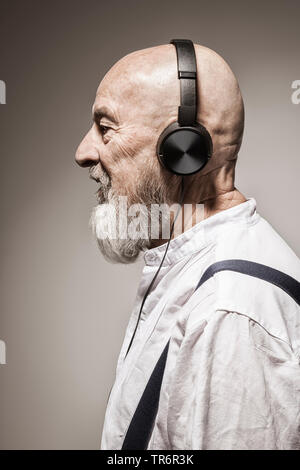 elderly bald head man listening to music with headphones, Germany Stock Photo