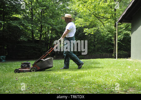 gardener mowing the lawn, Germany, North Rhine-Westphalia Stock Photo