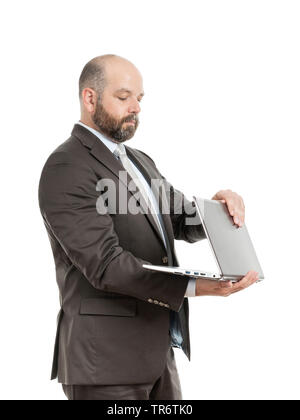 Middle-aged businessmann standing while working on his laptop, Germany Stock Photo