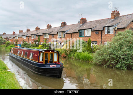 Canal boat passing Tollemache Terrace a row of cottages alongside the Shropshire Union Canal Chester England UK. May 2019 Stock Photo