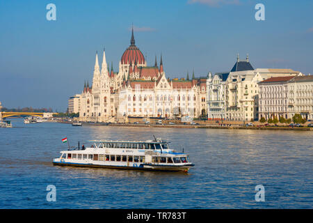 Tourist boat on the Danube with the Hungarian parliament building (Orszaghaz) in the background under a blue sky. Budapest, Hungary. Stock Photo