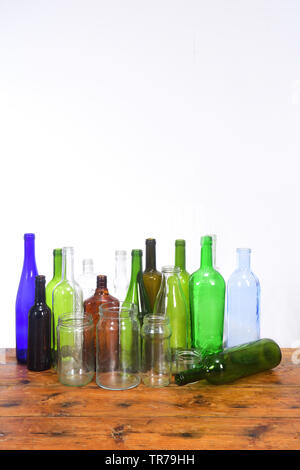 group of bottles and glass jars on a wooden table with white background Stock Photo
