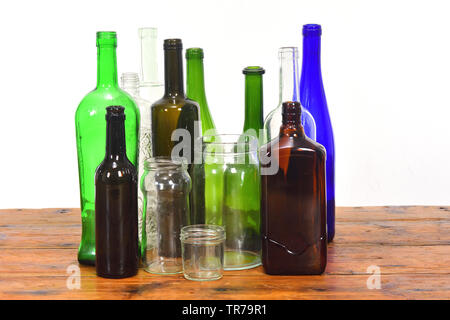 group of bottles and glass jars on a wooden table with white background Stock Photo