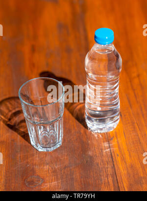 A plastic cup of carbonated water on a table at a park cafe with green ...