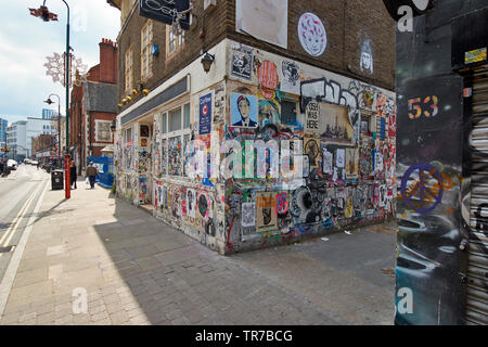 LONDON SPITALFIELDS BRICK LANE CLEVER GAFFITI AND WALL ART WITH A VIEW DOWN THE MAIN STREET Stock Photo