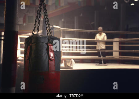 a sandbag hanging in front of a boxing ring have a janitor was cleaning Stock Photo