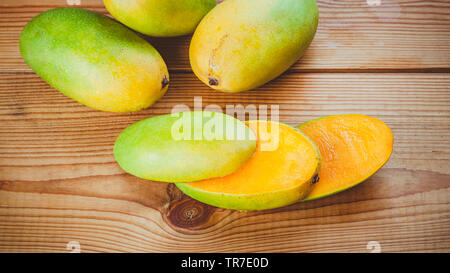 Close-up of fresh green Dashehari mangoes and its slices placed on wooden table.