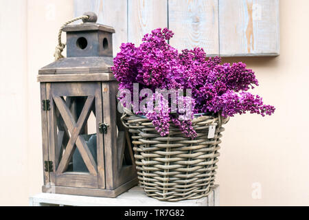 Wooden lamp and bouquet of purple lilac on woods table, home decor Stock Photo