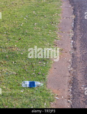 A plastic bottle lies discarded on a pavement next to a public street image with copy space Stock Photo