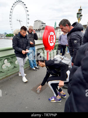 London, England, UK. Illegal Cup and Ball / 3 Cups Trick on Westminster Bridge, trying to con money from passing tourists