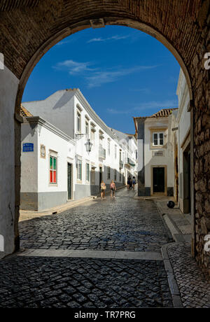 The arco da vila archway and cobbled street in the old town, Faro, the Algarve, Portugal Stock Photo