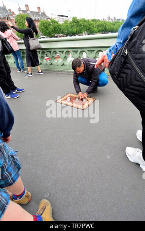 London, England, UK. Illegal Cup and Ball / 3 Cups Trick on Westminster Bridge, trying to con money from passing tourists