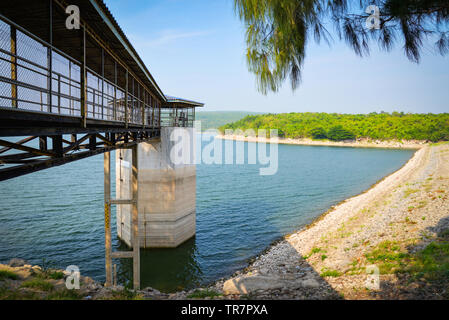 Landscape with dam lake mountain reservoir with tower Water level meter on bright day beautiful blue sky Stock Photo