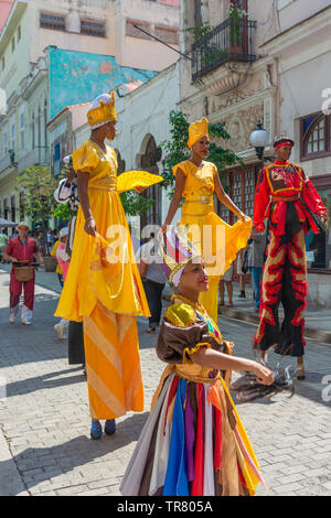 Colourfully dressed street performers in Old Havana, Cuba, some on stilts with a band playing following at the back. Stock Photo