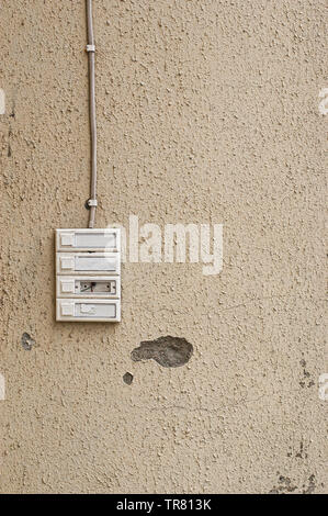 Four old and worn door bells on a beige wall. Stock Photo