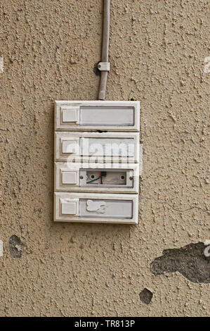 Four old and worn door bells on a beige wall. Stock Photo