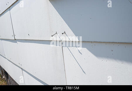 Asbestos cement sheets on a house where the nails has come loose. Stock Photo