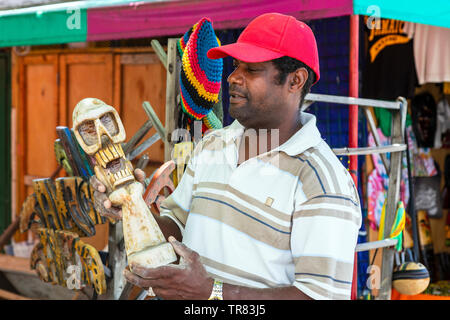 Local stallholder at a traditional craft market holding an ornamental skull that he has carved from wood, craft market, Ocho Rios, Jamaica, Caribbean Stock Photo
