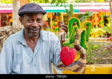 Local shopkeeper holding a wooden carvings that he made to sell to tourists at a local craft market, Ocho Rios, Jamaica, Caribbean Stock Photo
