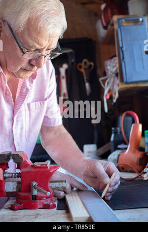 Senior Man Measuring Length Of Wood In Workshop Stock Photo