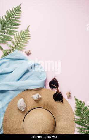 Feminine summer fashion composition with blouse, hat, sunglasses, fern, seashell on pink background. Flat lay, top view minimalist clothes collage. Tr Stock Photo