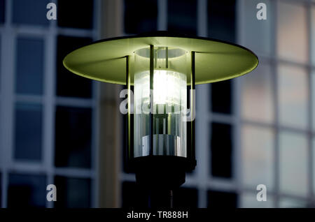 antique street lantern lights up at night in front of blurred building Stock Photo