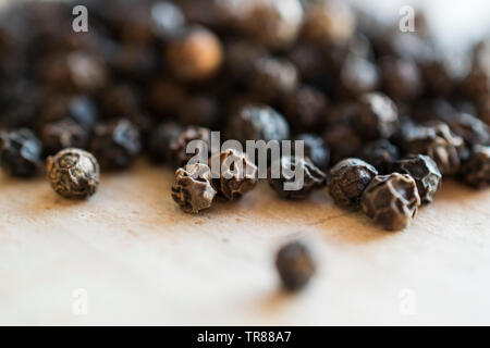 Close up Macro shot of black peppercorns on a chopping block in the kitchen Stock Photo