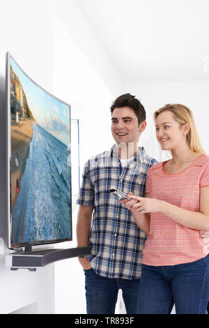 Young Couple With New Curved Screen Television At Home Stock Photo