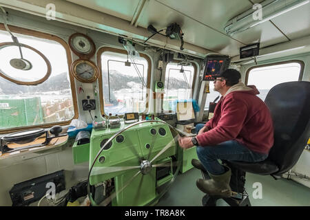 Captain steering Ferry Marine Voyager, which takes foot passengers and cargo between Burgeo and the outports of Grey River and Francois, leaving the d Stock Photo