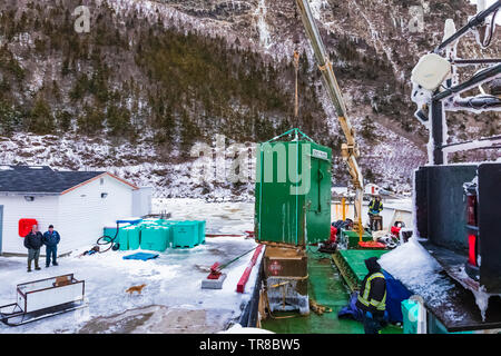 Unloading and transporting cargo at the outport of Grey River, which is snuggled along a fjord, viewed from the ferry Marine Voyager, Newfoundland, Ca Stock Photo