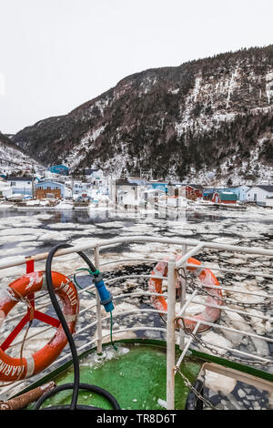 Waterfront with floating pancake ice at the outport of Grey River, which is snuggled along a fjord, viewed from the ferry Marine Voyager, Newfoundland Stock Photo