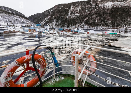 Waterfront with floating pancake ice at the outport of Grey River, which is snuggled along a fjord, viewed from the ferry Marine Voyager, Newfoundland Stock Photo