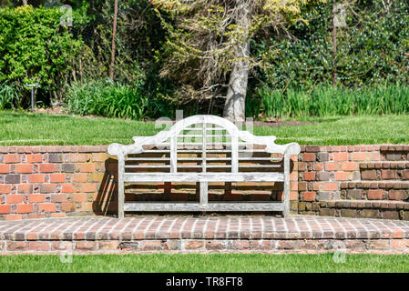 wooden bench on a brick patio with a brick wall in the background Stock Photo